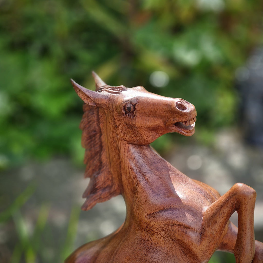 Pferde Statue aus Holz auf Stein mit grünem Hintergrund