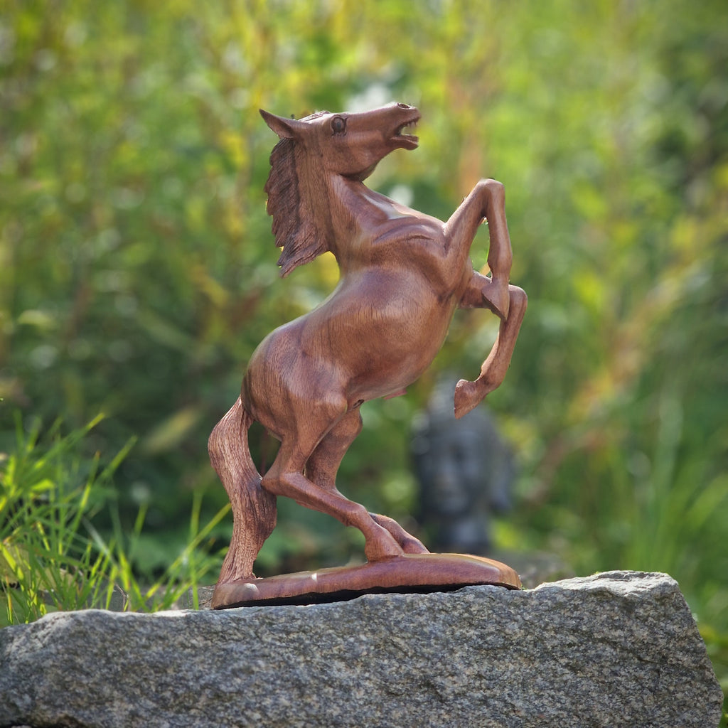 Pferde Statue aus Holz auf Stein mit grünem Hintergrund